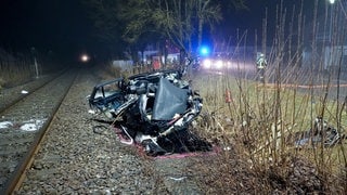 Ein völlig zerstörter Pkw liegt nach einer tödlichen Kollision mit einem Zug am Rande eines Gleisbettes.