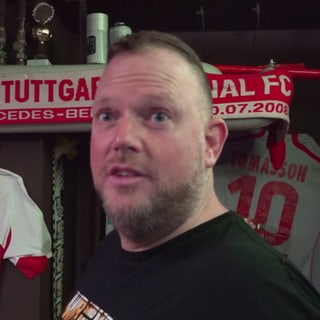 Daniel steht vor zwei hängenden VfB-Trikots und einem VfB-Schal.