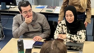 Teilnahme am Integrationskurs: Eine Frau mit Kopftuch und ein Mann sitzen am Schreibtisch und lernen.