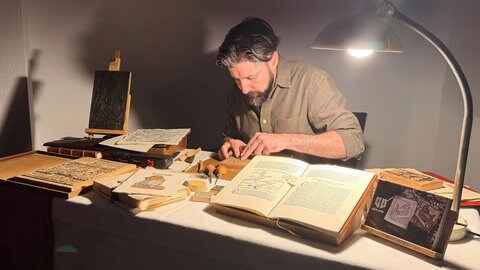 Jorge Larguito präsentiert einen originalgetreu hergestellten Druckstock, der eine über 500 Jahre alte Drucktechnik wieder erlebbar macht.