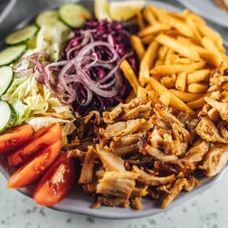 Dönerfleisch liegt neben Pommes und Gemüse auf einem Teller. Wie gut ist Döner aus dem Kühlregal im Supermarkt oder Discounter?