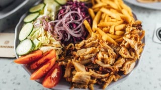 Dönerfleisch liegt neben Pommes und Gemüse auf einem Teller. Wie gut ist Döner aus dem Kühlregal im Supermarkt oder Discounter?
