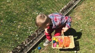 Ein Kind sucht in einem Garten Eier (Symbolbild)