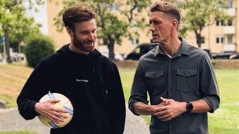 Nils Petersen läuft mit Arbeitskollege Jonas durch die Fußgängerzone.