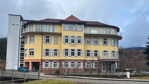 Ein Blick auf die alte geschlossene Klinik in Forbach, ein gelbes vierstöckiges Gebäude mit Fensterläden. Immer mehr Kliniken schließen, weswegen länger auf den Rettungswagen gewartet werden muss.
