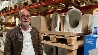 Ein Mann steht vor einem Regal mit Toilettenschüsseln: Die Zander-Gruppe hat die insolvente Firma Laeis Sanitär aus Trier übernommen.