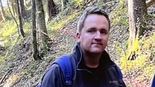 Ein Mann mit kurzen braunen Haaren schaut in die Kamera.
