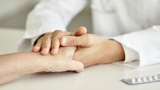 Ein Arzt hält tröstend eine Hand.