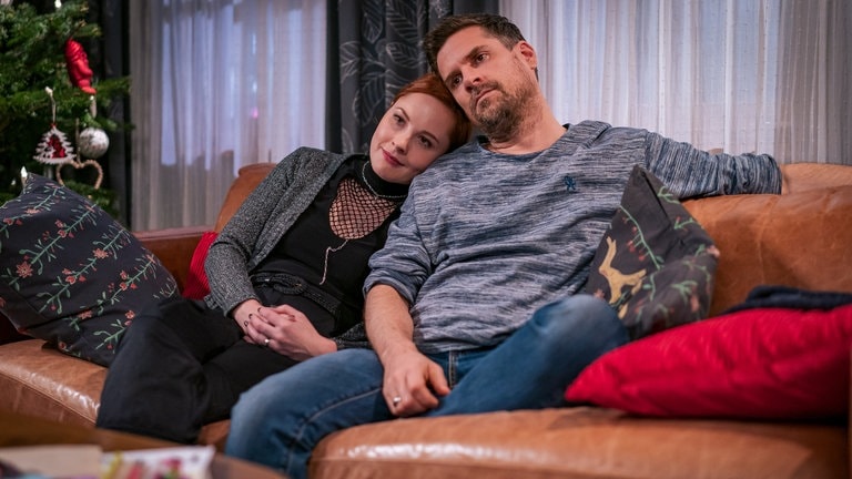 Lissy (Elinor Eidt) und Andreas (Ralph Gassmann) sitzen aneinandergekuschelt auf dem Sofa