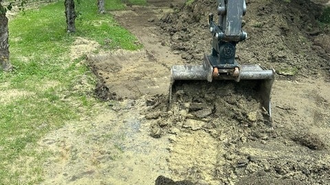 Ein Bagger entfernt nach den Überflutungen vor einem Jahr Schlamm von einem Campingplatz.