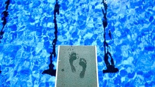 Symbolbild: Fußabdrücke eines Badegastes sind auf dem Ein-Meter-Brett im Freibad zu sehen.