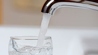 Wasser strömt aus der Leitung in ein Glas
