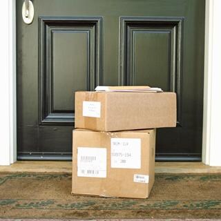 Vor einer Haustüre stehen ein Paket, das vom Paketdienst geliefert wurde. 