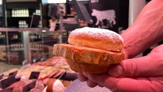 Ein Berliner bestäubt mit Puderzucker, dazwischen eine Scheibe Fleischkäse. Eine Mössinger Metzgerei bietet zur Fasnet den "Fasnets-Fleischkäse" an.