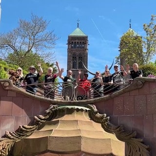 Menschengruppe winkt von einer Brücke