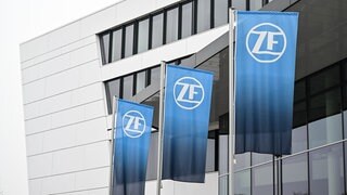 Drei Fahnen mit dem Logo der ZF Friedrichshafen AG wehen vor der Verwaltungszentrale des Konzerns. ZF verkürzt in Friedrichshafen die Arbeitszeit von 2.800 Mitarbeitern.