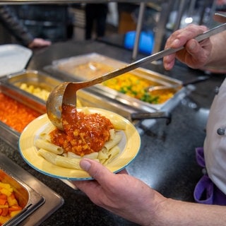 Ein Koch serviert in einer Mensa ein veganes Gericht mit Nudeln und Soja-Bolognese. Laut einer Studie der Uni Konstanz boomt veganes Essen in Hochschulmensen.