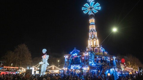 Eine etwa acht Meter hohe Leuchtpuppe des Großpuppentheaters "Dundu" wird über den Weihnachtsmarkt Stuttgart geführt. 