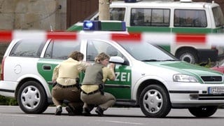 In Deckung gehen Polizeibeamtinnen hinter ihrem Wagen am Freitag, 26. April 2002 vor dem Gutenberg-Gymnasium in Erfurt. In einem  Amoklauf hat ein ehemaliger Schüler in diesem Gymnasium 17 Menschen und sich selbst erschossen. Mindestens vier Menschen wurden verletzt. 