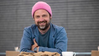 Der Schauspieler und Musiker Christoph Letkowski lacht in die Kamera.