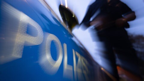 Eine Polizistin steht neben einem Polizeifahrzeug.