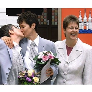Angela Gobelin und Verena Lappe küssen sich am 1.8.2001 im Innenhof des Rathauses Altona in Hamburg. Rechts neben ihnen die Senatorin für Gleichstellung Krista Sager.