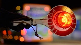 Eine Polizeikelle fordert Autofahrer zum Anhalten auf (Symbolbild): Zivilpolizisten haben in Kaiserslautern einen 18-jährigen Raser gestoppt.