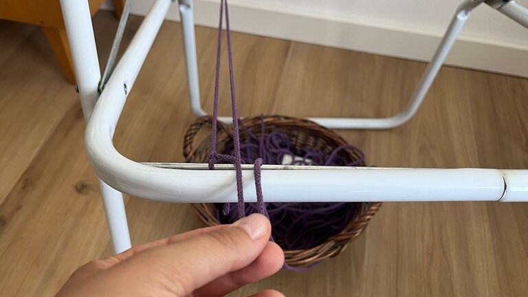 Nun wird das Garn wieder doppelt nach unten geführt und von oben nach unten hinten links um die Stange gewickelt...