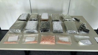Tabletten, Waffen und abgepackte Drogen liegen auf einem Tisch: Drogen im Wert von einer Million Euro hat die Polizei in einer Lagerhalle in Worms gefunden. 