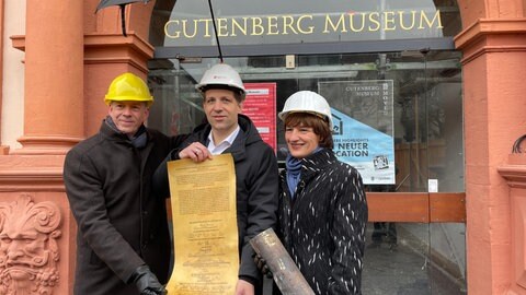 Der Direktor des Mainzer Gutenberg-Museums, Ulf Sölter, der Mainzer Oberbürgermeister Nino Haase und die scheidende Kulturdezernentin Marianne Grosse (v.l.n.r.) mit der Urkunde aus der Zeitkapsel des Gutenberg-Museums von 1961