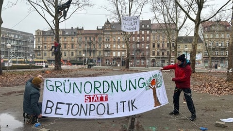 Die Protestierenden haben Forderungen auf Laken geschrieben, die sie in die Platanen vor dem Badischen Staatstheater in Karlsruhe hängen. 