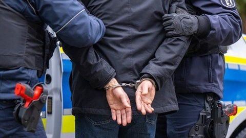 Mann wird in Handschellen abgeführt (Symbolbild). Kripo Ludwigshafen nimmt Paar nach Schockanruf in Pirmasens fest.
