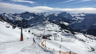 Skifahrer im Skigebiet Damüls in Vorarlberg, im Hintergrund sind beschneite Berggipfel zu sehen. 