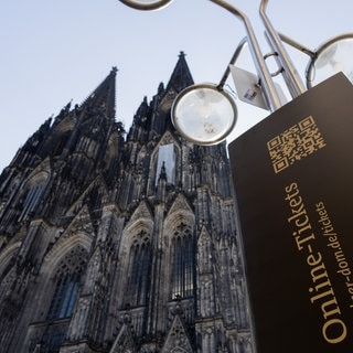 Blick auf den Kölner Dom und ein Hinweisschild, das auf Online-Tickets für die Besichtigung des Doms hinweist.