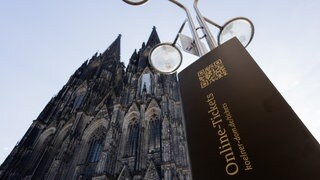 Blick auf den Kölner Dom und ein Hinweisschild, das auf Online-Tickets für die Besichtigung des Doms hinweist.