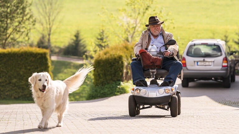 Hermann auf seinem Elektromobil und Hofhund Willi vor dem Fallerhof