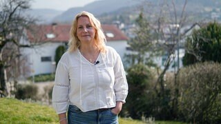 Christine steht bei sich zu Hause im Garten und schaut in die Kamera. Hinter ihr ist die schwäbische Alb zu sehen. Der Garten war ihr Kraftort, als sie stark unter Panikattacken gelitten hat. 