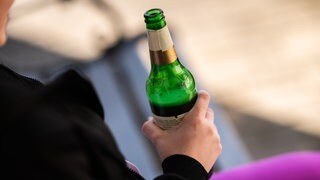 Eine Jugendliche hält eine Flasche Bier in der Hand. In Bad Kreuznach soll eine Verbotszone für Alkohol ausgewiesen werden.