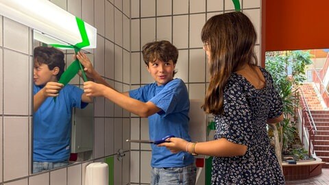 Zwei Schülerinnen kleben grüne Lianen über den Toilettenspiegel. Schüler des Carlo-Schmid-Gymnasiums in Tübingen übernehmen die Gestaltung ihrer Schultioletten selbst.