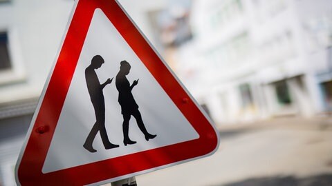 Ein "Smombie"-Warnschild in Baden-Württemberg warnt vor unachtsamen Verkehrsteilnehmern mit Smartphone.