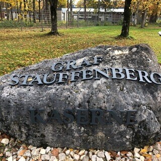 Auf einem Stein steht "Graf Stauffenberg Kaserne", im Hintergrund sind Kasernengebäude zu sehen. Das Bundesverteidigungsministerium plant, ehemalige Bundeswehrliegenschaften zu behalten.