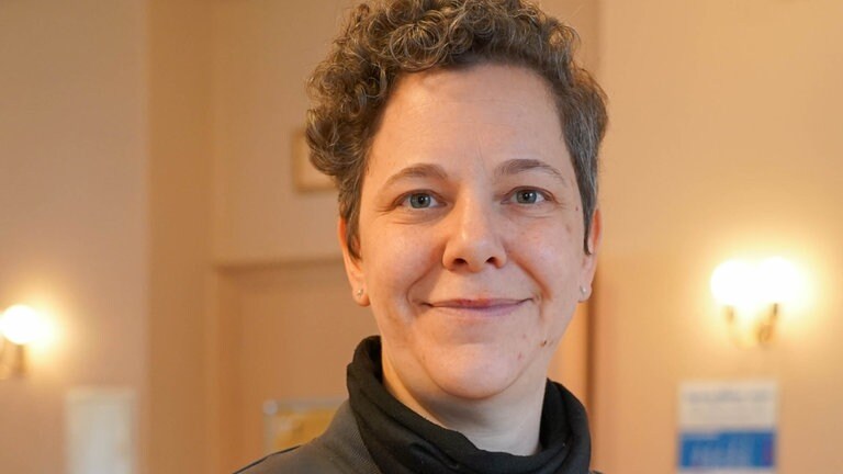 Frau mit grauen Locken lächelt in die Kamera.
