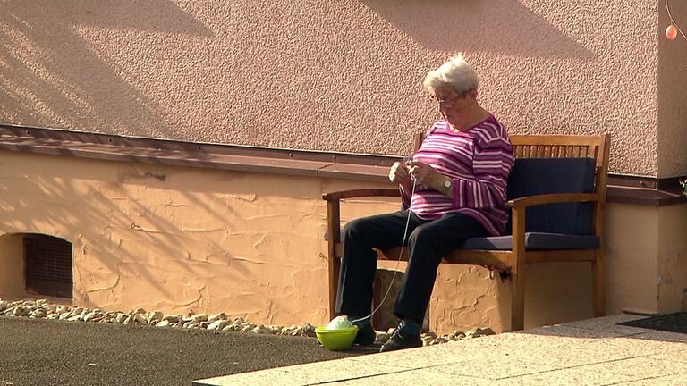 Anwohnerin strickt vorm Haus