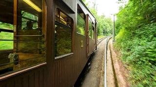 Die Stuttgarter Seilbahn fährt durch einen Wald den Berg zum Waldfriedhof hinauf.