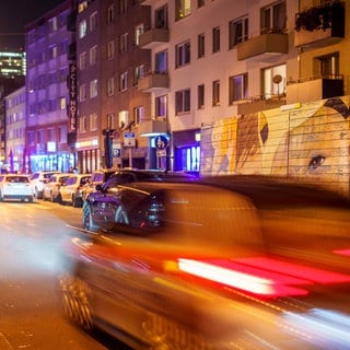 Symbolbild: Verkehr fließt durch eine Stadt. Im Vordergrund sieht man ein Auto, das den Eindruck erweckt, dass es schnell fährt. 