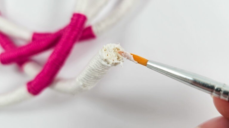 Die Schnittkanten mit etwas Textil- oder Bastelkleber (muss transparent trocknen) versiegeln.