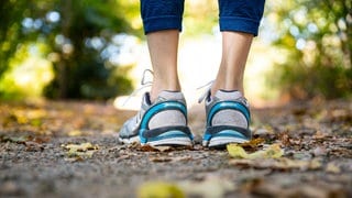 Ein paar Füße mit Turnschuhen im Wald.  (Symbolbild) Der Streit zwischen der ehemaligen Profisportlerin und Lauftrainerin Caroline Hingst und den rheinland-pfälzischen Landesforsten ist beigelegt. 