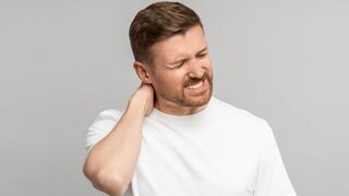 Mann mit Nackenschmerzen | Intensive Handynutzung: Was tun gegen Schmerzen in Nacken und Schultern?