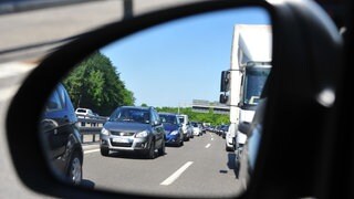 Zahlreiche im Stau stehende Fahrzeuge, die man in einem Rückspiegel sieht (Symbolbild). 