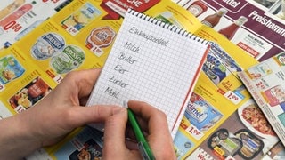 Eine Frau notiert sich Sonderangebote auf einem Einkaufszettel: Wer mit der Hand auf Papier schreibt kann sich Dinge besser merken, als wenn man in einen Bildschirm tippt. Warum ist das so?